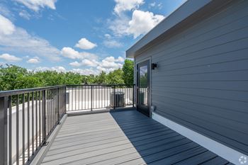 A balcony with a railing and a door leading to a house.